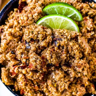 Close up overhead shot of a bowl of vegan ground chorizo with two lime wedges on top