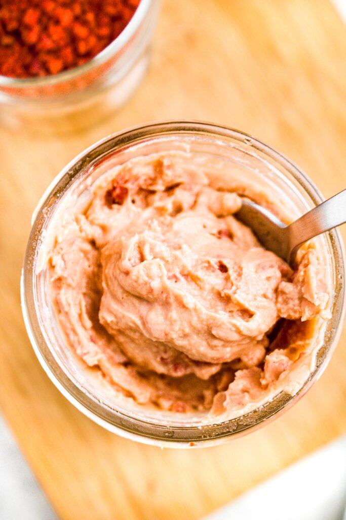 Overhead close up photo of a spoon digging into a clear glass mason jar of creamy bacon soup substitute