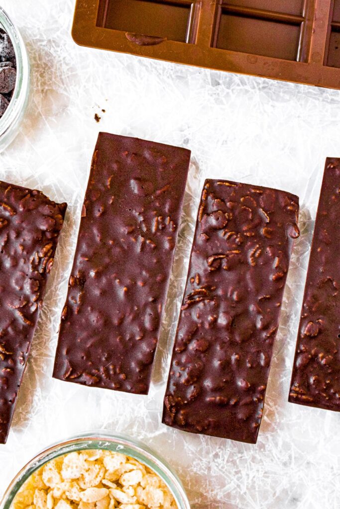 Overhead photo of crunch vegan chocolate bars with a bowl of rice crispy cereal to the bottom left