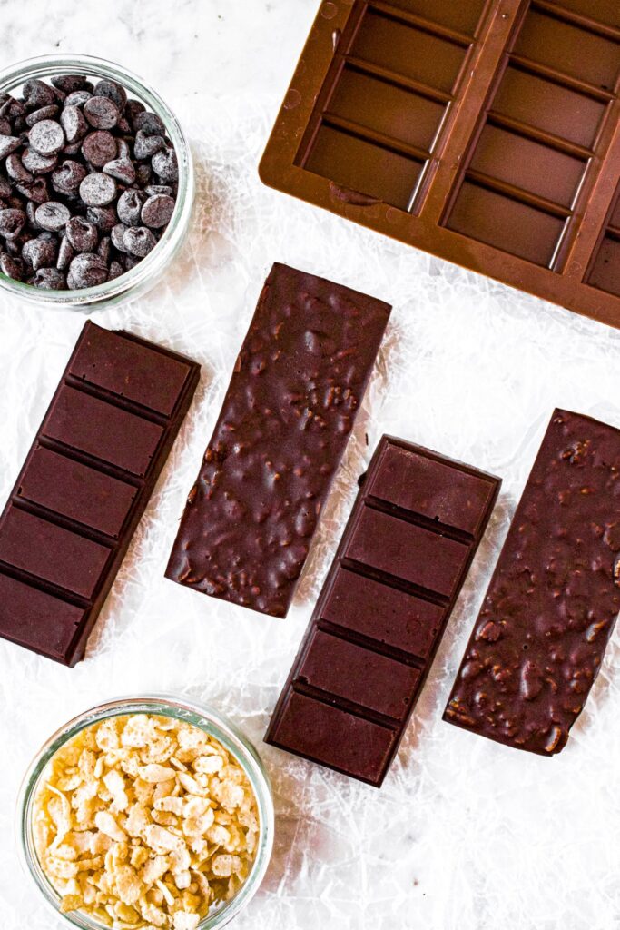 Overhead photo of 4 homemade chocolate crunch bars with a silicone chocolate bar mold in the upper right corner