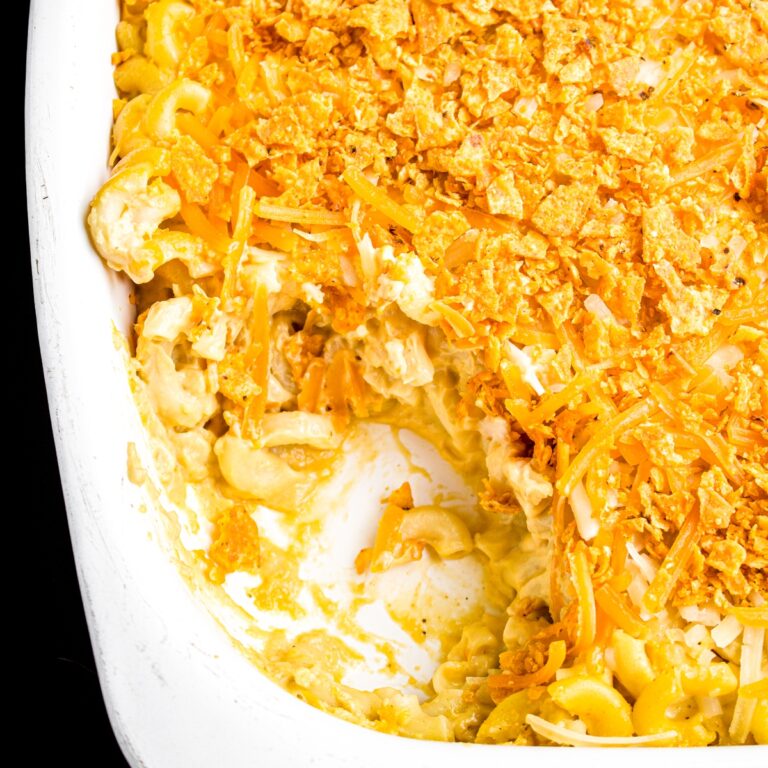 Overhead zoomed in view of a rectangular white casserole dish of vegan baked mac and cheese sprinkled with Sweet Chili Doritos