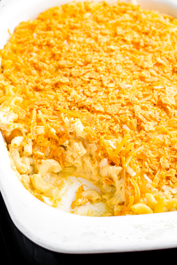 Overhead view of a square white baking dish of vegan mac and cheese sprinkled with dairy free Sweet Chili Doritos