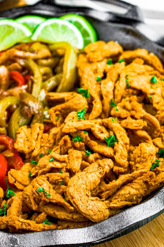 Close up shot of cooked soy curls for vegan chicken fajitas sprinkled with green herbs