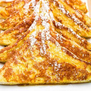 Close up overhead photo of a plate of vegan French toast with powdered sugar sprinkled on top