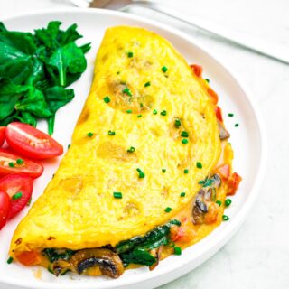 Overhead photo of a just egg omelette on a round white plate sprinkled with sliced chives