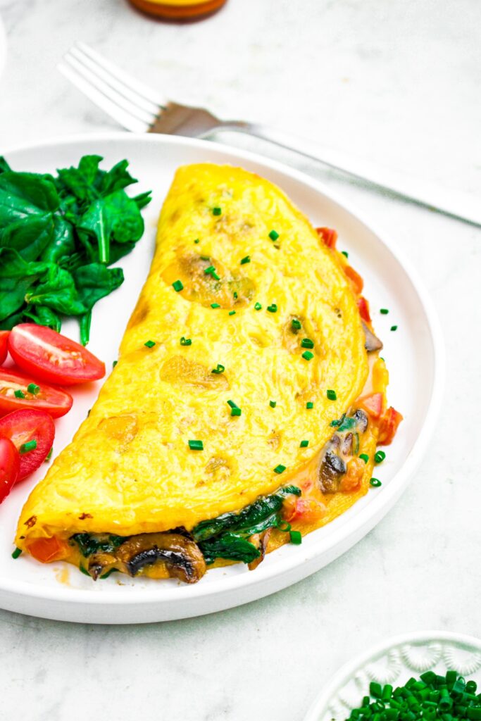 Overhead photo of a just egg omelette on a round white plate sprinkled with sliced chives
