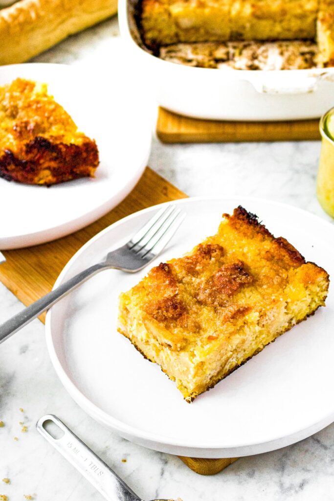 Close up photo of a slice of vegan pineapple souffle on a round plate with a fork next to it