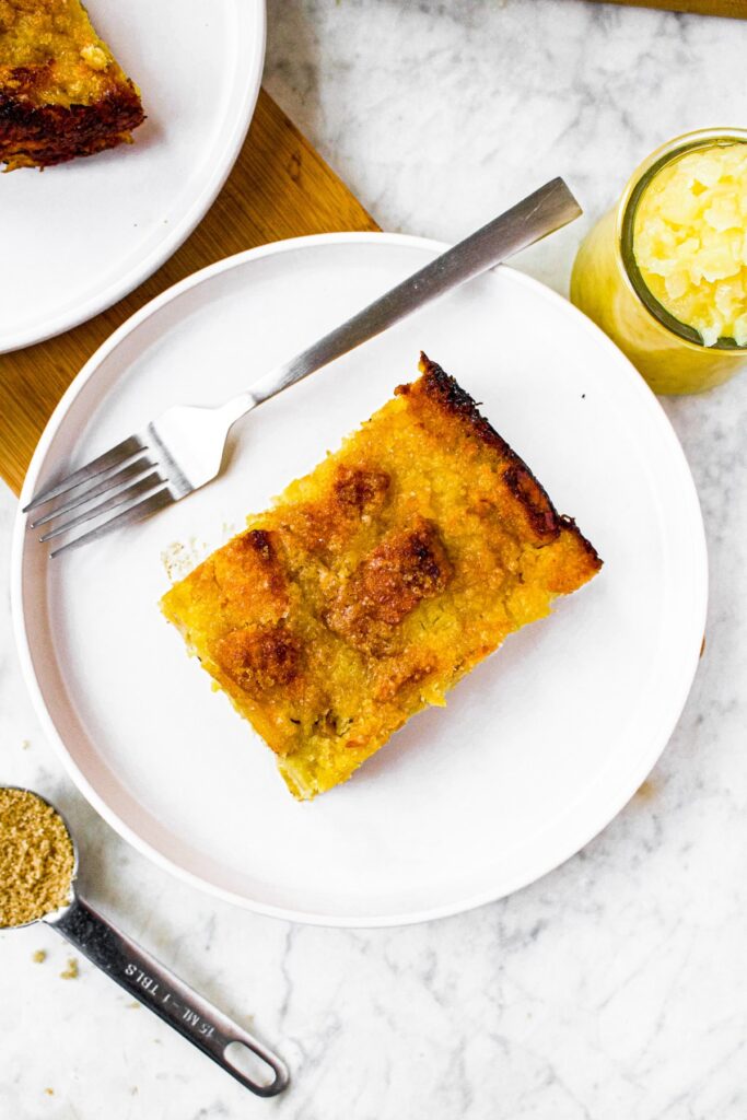 Overhead photo of a rectangular piece of healthy pineapple stuffing on a plate with a fork on one side and a jar of crushed pineapple on the other