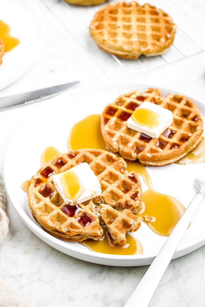 Head on photo of a vegan protein waffle with a triangle cut out of it and a fork to the right