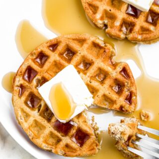 Overhead close up photo of a high-protein waffle topped with vegan butter and maple syrup