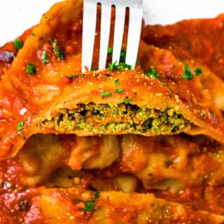 Close up shot of a vegan ravioli square cut in half showing the dairy free spinach and tofu ricotta filling.