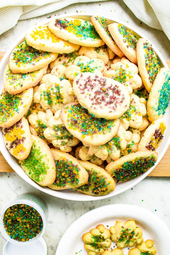 Overhead photo of a vegan cookie plate decorated for spring next to a jar of multicolored sprinkles