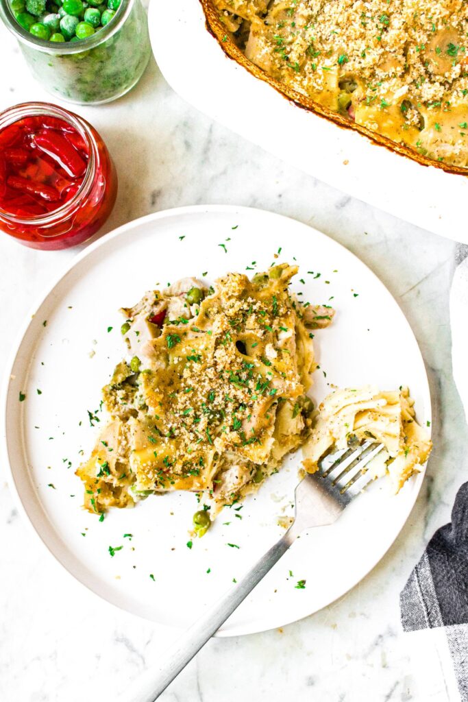 Overhead shot of a slice of vegan tuna casserole on a plate with a fork next to it that has a bite of the casserole on it.