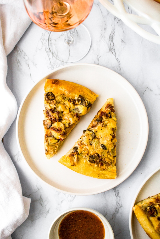 This easy vegan white pizza recipe is impossible to resist! Marinated vegetables like sun-dried tomatoes, garlic, olives, artichokes, and mushrooms are nestled between two layers of thick and creamy dairy-free white sauce. This vegan pizza recipe uses a vegan white sauce that’s made without any vegan cheese, milk, or cashews! It’s a fun and easy option for plant-based pizza night that will seriously impress!