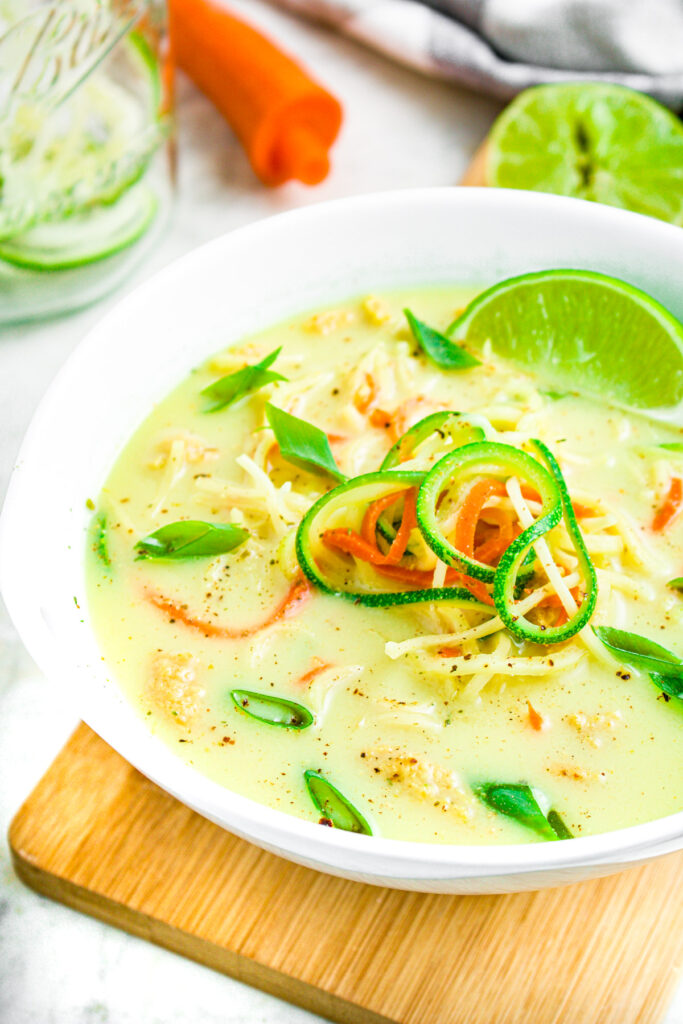 Overhead close up photo of a bowl of creamy green curry ramen with a lime wedge in it